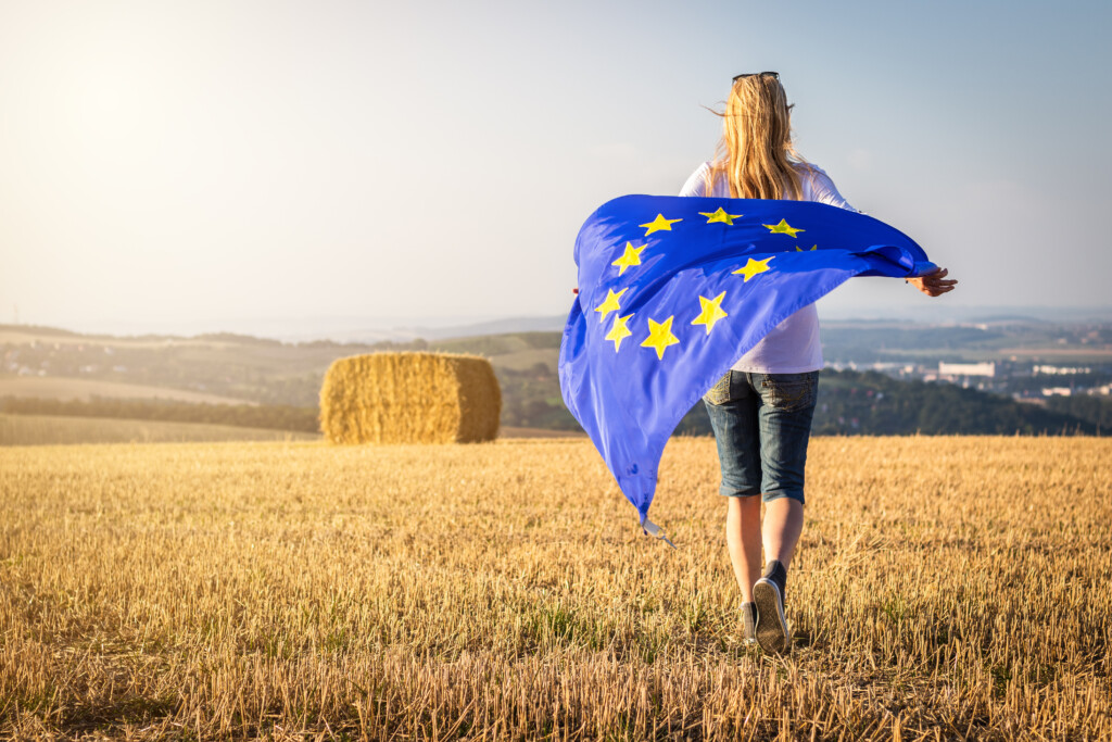 osoba koja drži zastavu EU dok šeta poljima